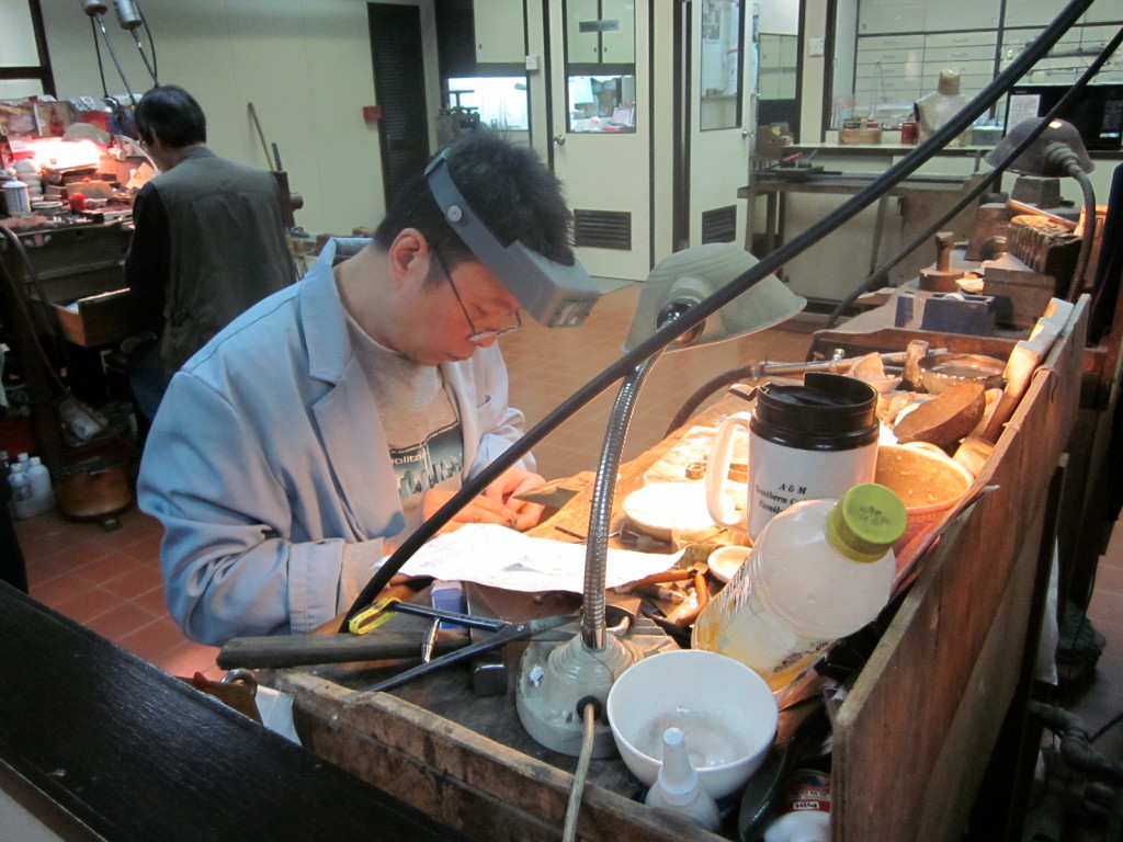 Worker at a jade factory setting a ring.