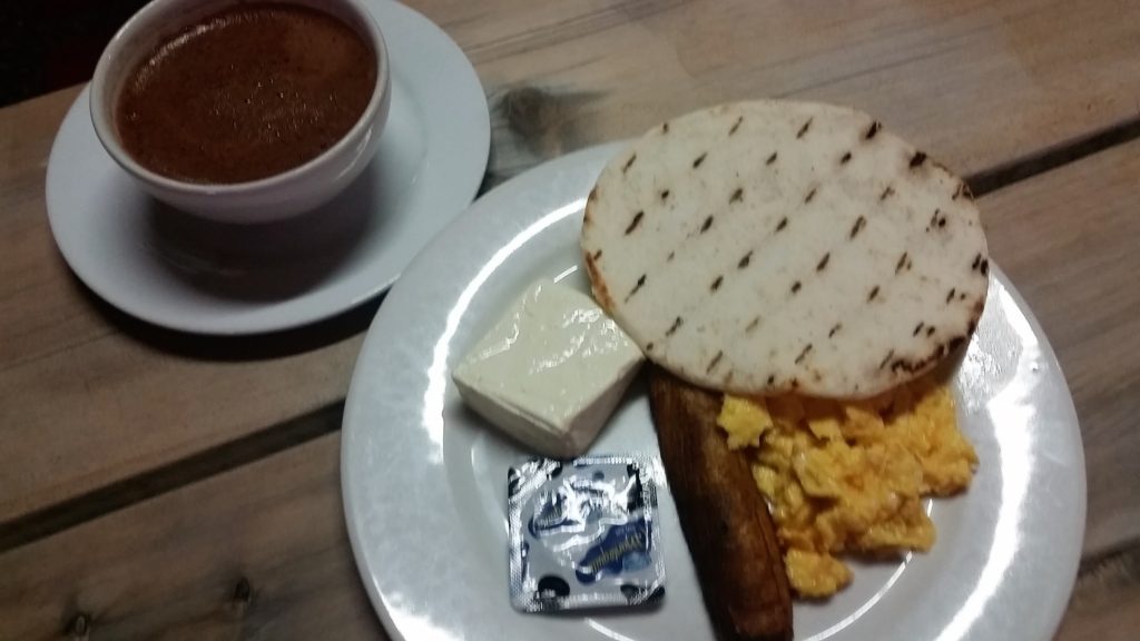 Colombian breakfast of hot chocolate, eggs, empanada, cheese and sausage